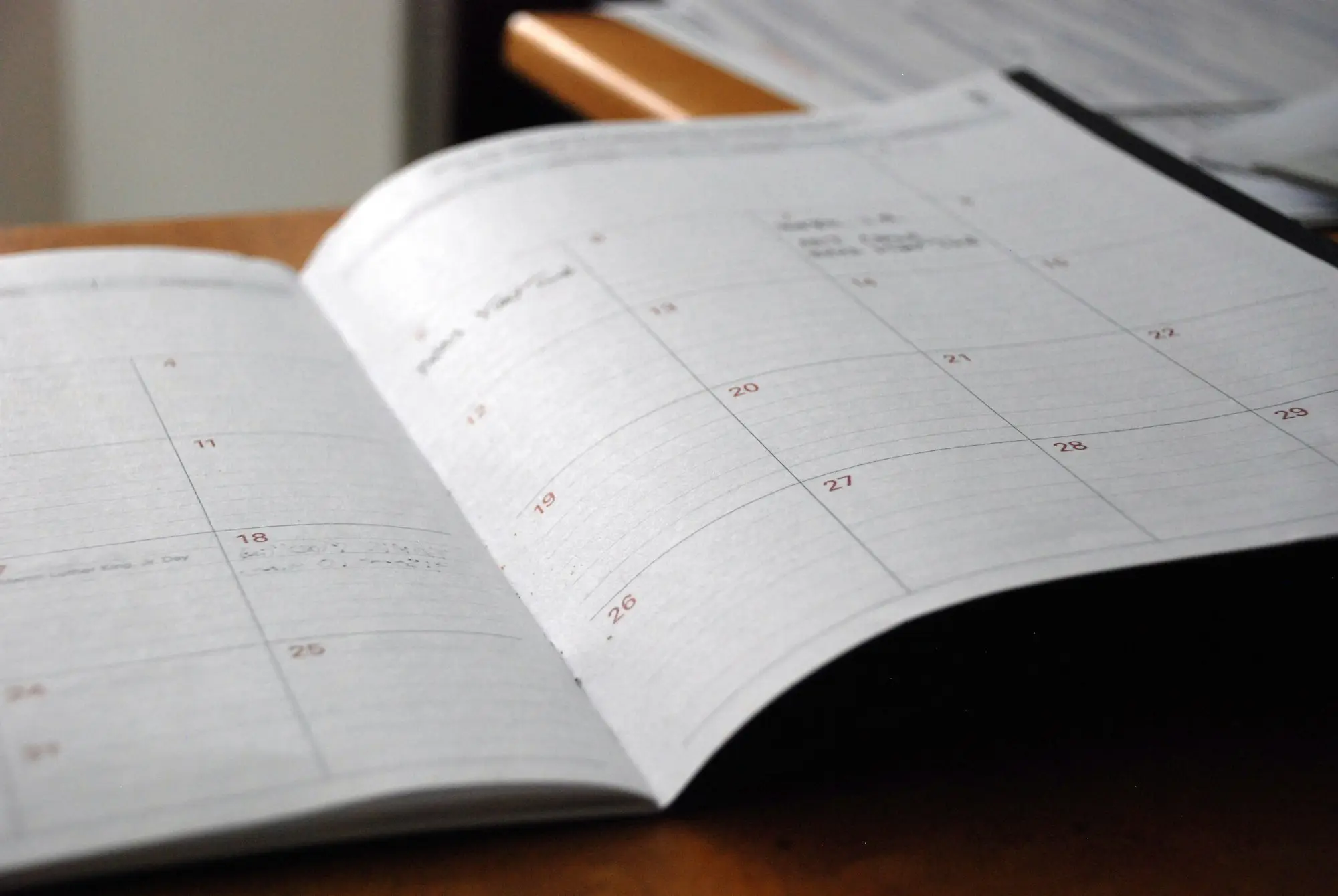 Open monthly planner diary lying on a wooden desk