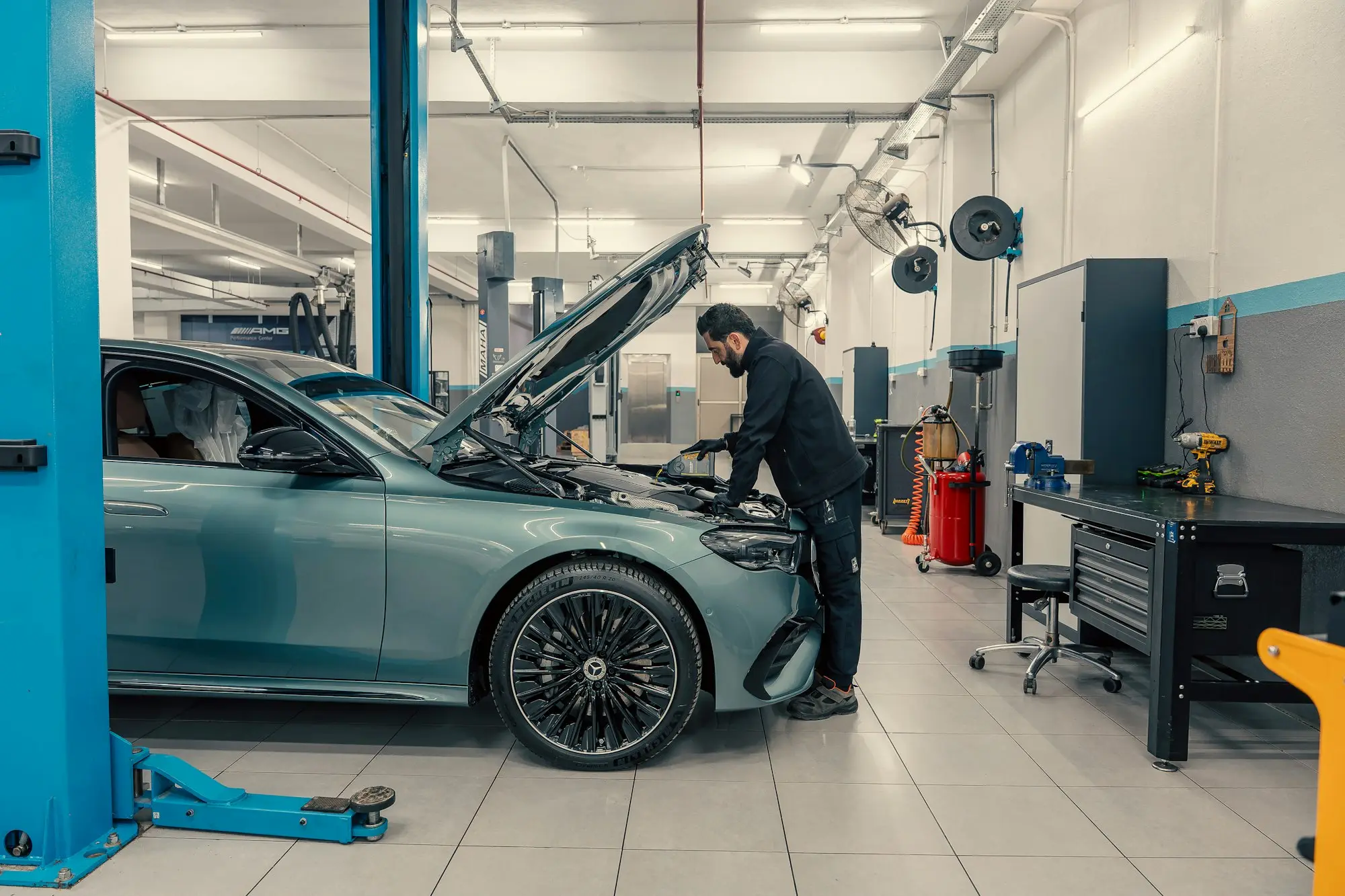 Mechanic leaning into the engine bay of a car in a clean, well-lit service workshop